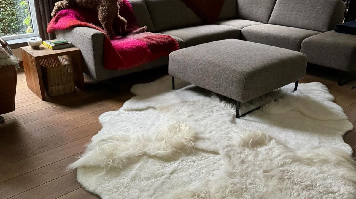 Wit schapenvacht patchwork tapijt bij een grijze hoekzetel met een hond