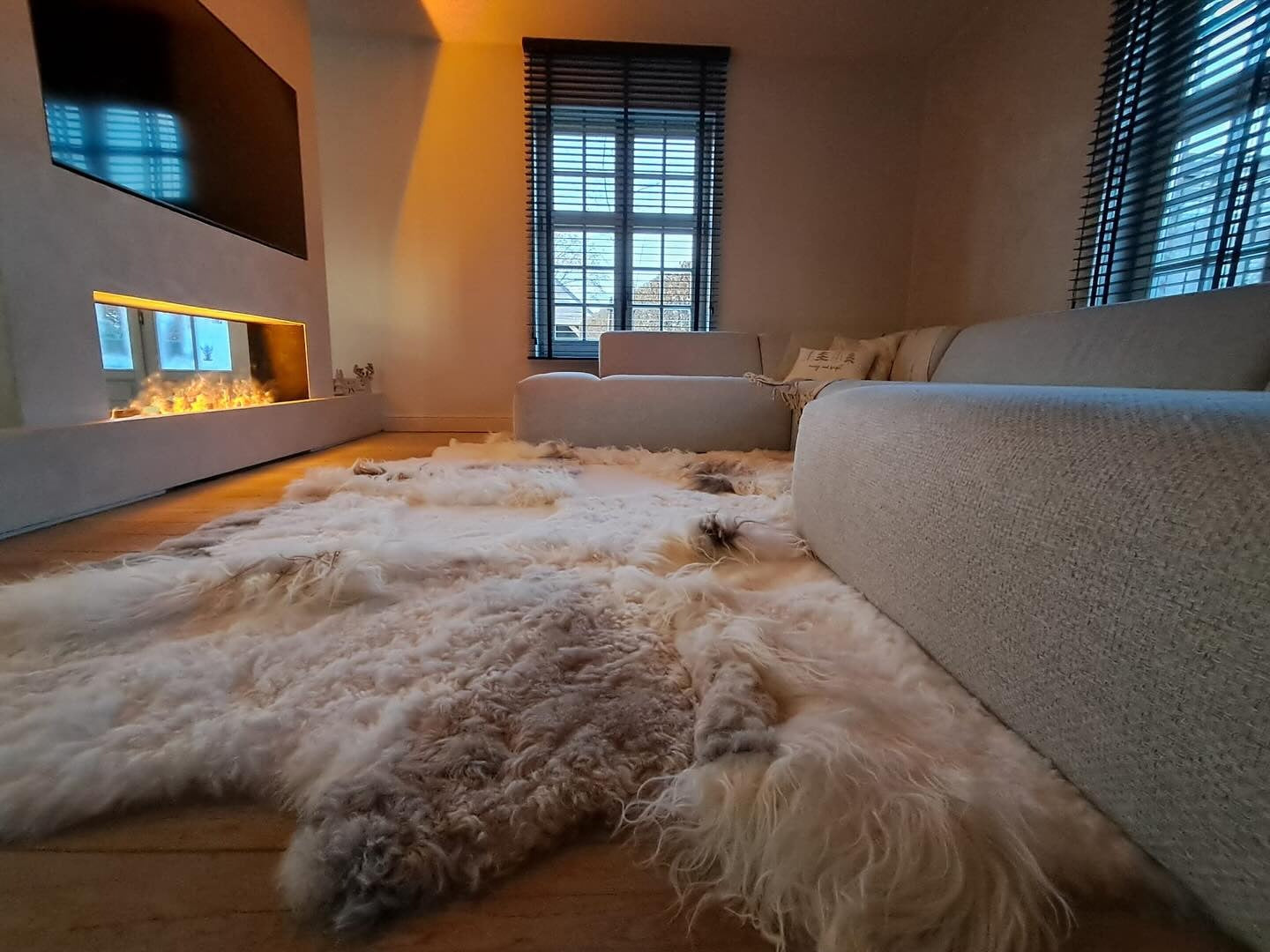 Melange patchwork tapijt van IJslandse schapenvachten met lang haar in een lichte woonkamer